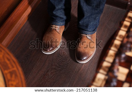man in blue jeans and yellow boots standing on a dark floor