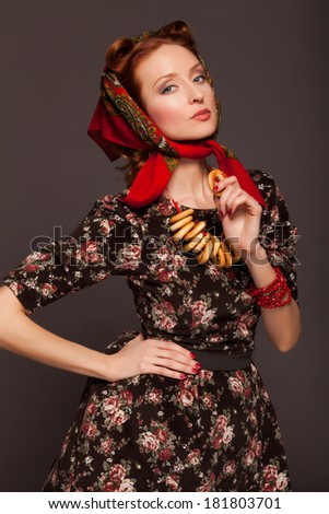 Girl in Russian style posing in red kerchief and bagels on the neck.