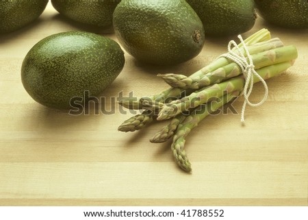 Avocados and asparagus on butcher block surface