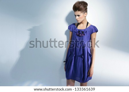 young woman in blue dress standing posing on light background