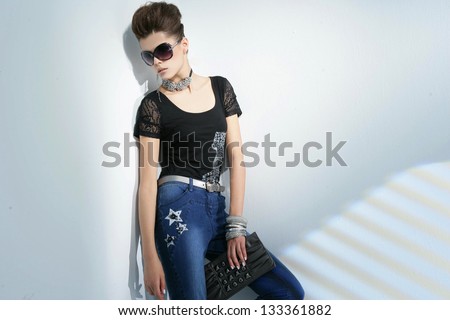portrait of young woman wearing sunglasses holding purse Ã¢Â?Â?light background