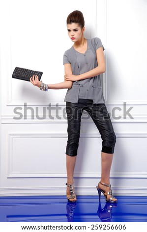 Full body portrait of young fashion model  holding purse posing in studio