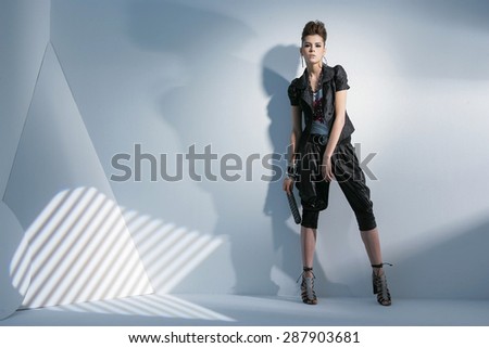 Full body fashion model wearing modern cloth holding purse posing