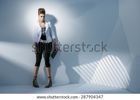 Full body fashion model wearing modern holding purse posing in light background