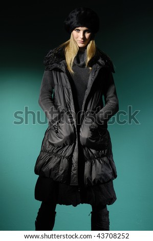 Fashion model in winter dress on blue light studio