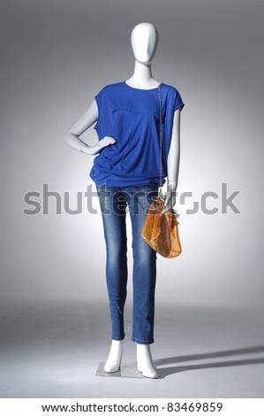 Mannequin dressed in jeans with bag on light background