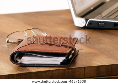 a pen an address book, glasses and laptop