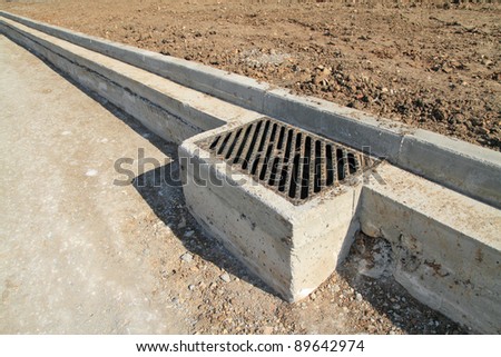 Concrete curb and drainage well at road construction site. The road is ready to be asphalted