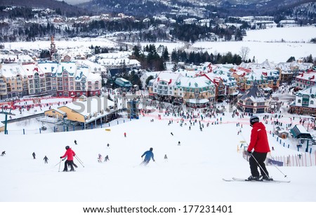 MONT-TREMBLANT, QC, CANADA -FEBRUARY 9: Skiers and snowboarders are sliding down the main slope at Mont-Tremblant Ski Resort on February 9, 2014. It is the best ski resort in Eastern North America.