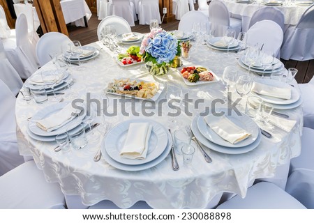 Elegant banquet tables prepared for a conference or a party and covered with a white tablecloth and decorated with flowers for guests