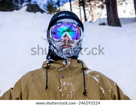 Portrait of bearded young man in sunglass a fallen face in the snow at the ski resort