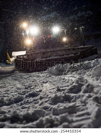Snowcat preparing a slope at night in high mountains at skiing resort of the North Caucasus Elbrus