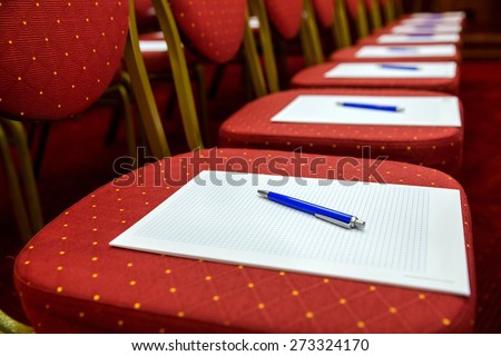 Closeup of notepad with pen for agenda on chairs in empty corporate conference room before business meeting