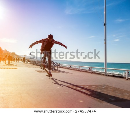 Silhouette of Skateboarder jumping in city on background of promenade and sea