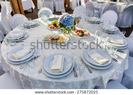 Elegant banquet tables prepared for a conference or a party and covered with a white tablecloth and decorated with flowers for guests