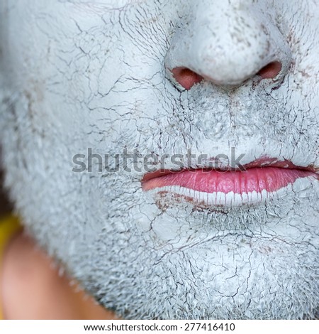Men face closeup on facial blue clay mask. Treatment and care for the face skin