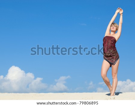 Attractive beautiful woman pulls his hands up against the blue sky with clouds