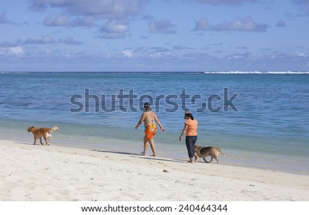 RAROTONGA, COOK ISLANDS - FEBRUARY 5, 2009: Women walking the dog on the tropical beach of Rarotonga, Polynesia.