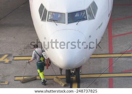 DUESSELDORF, GERMANY - SEPTEMBER 25, 2011: High angle view of Germania airplane cockpit  and ground technician. The ground technician removes chocks from the front tires.