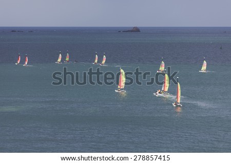 SAINT-MALO, FRANCE - JULY 6, 2011: Group of teenagers learning catamaran sailing on the coast of Saint-Malo. Their Hobie Cat Teddy catamarans are 13 feet long and have a great buoyancy.