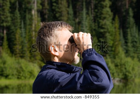 park ranger watching closely wildlife - with his field glass - adobe RGB
