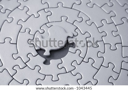 grey jigsaw with the missing piece laying above the space - pieces fitting together in form of a spiral