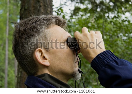 portrait of a park ranger - watching closely wildlife with his field glass