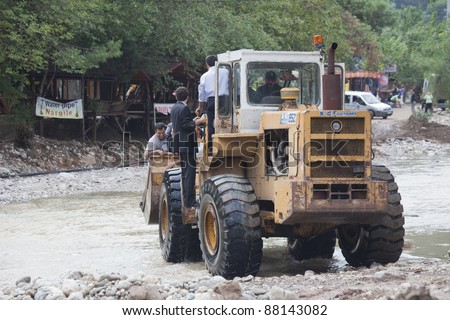OLYMPOS, TURKEY - OCTOBER 14:  Politician and civil servants ride in a shovel of earth mover used as a ferry for crossing flooded road after natural disaster on October 14, 2009 in Olympos, Turkey.
