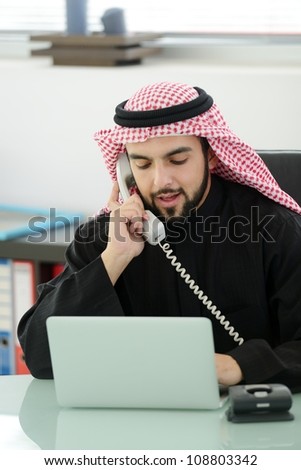 Portrait of a smart arabic business man using laptop and talking  on the phone