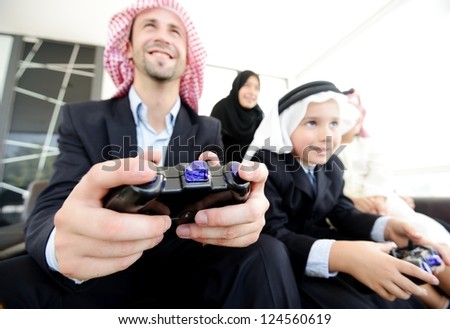 Happy Arabic family playing at home with video game controllers