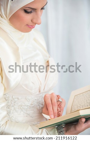 Delicately dressed woman reading holy islamic book Koran
