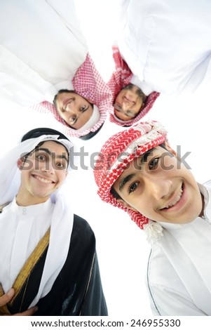 Happy group of Arabic people with heads together in circle over sky background