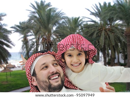 Arabian man and little kid on beach