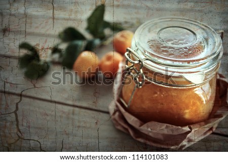 Homemade Mandarin marmalade in jar with rustic textures.