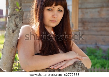 Portrait of young beautiful woman leans on fencing.