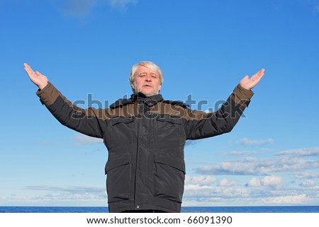Mature man with grey hair relaxing at the Baltic sea and blue sky on the background.