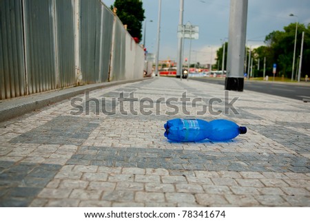 Polluted city series. Wasted PET bottle on sidewalk. Soft focus image, focus on the bottle.