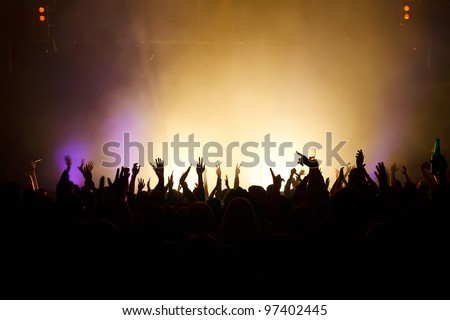Hands in the air silhouetted against great stage lights.