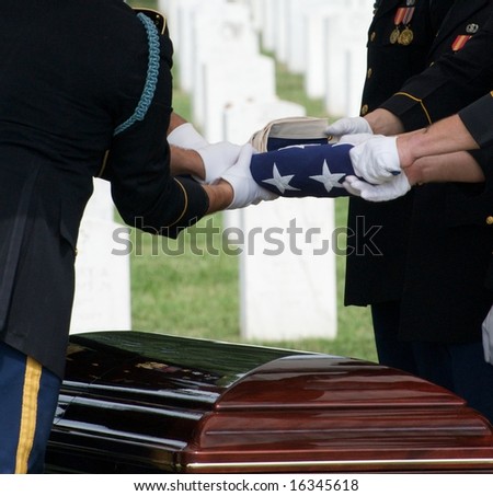 Flag being folded above casket during burial at Arlington National Cemetery