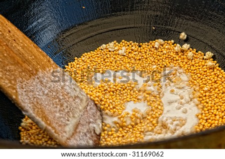 Kettle corn being stirred while sugar is added