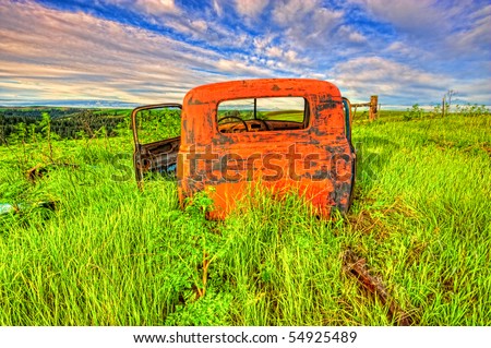 Abandoned and very old truck covered with rust and peeling pain in a field