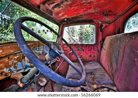 Horizontal photo of inside of old, abandoned pickup truck with bullet holes in windows