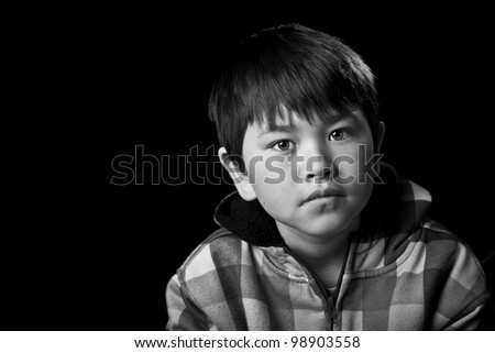 Cute young asian boy with serious look on black background in black and white