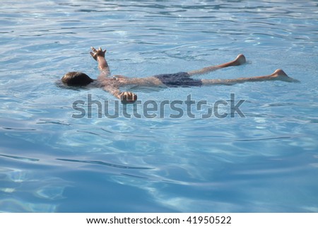 The boy in open pool lies on a water surface.