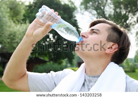 The young man drinks water from a bottle