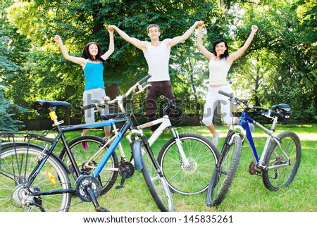 Three happy cyclists jumping in the park