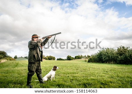 Hunter with dog aiming with his rifle