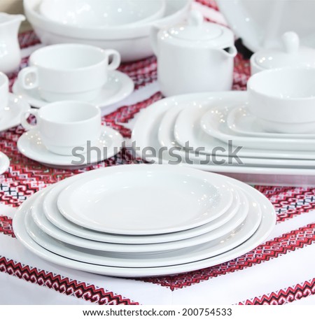 complete set of white ware, dinner service on a cloth with a red national Ukrainian pattern