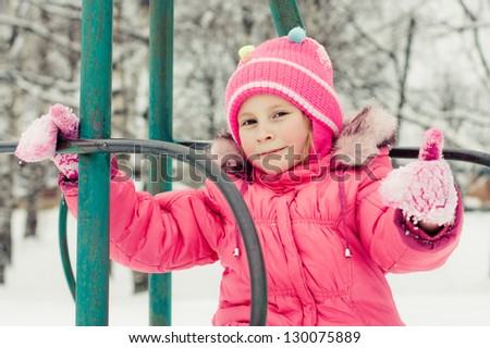 Beautiful happy kid in the red jacket in the winter outdoors.