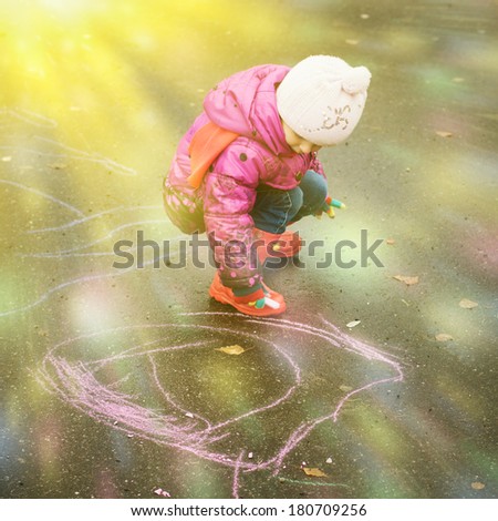 Child draws with chalk on the playground.